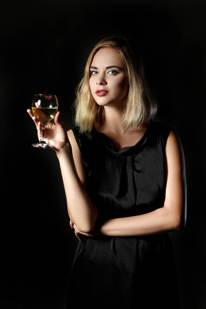 Beautiful blonde woman with glass of white wine on black background - Foto, afbeelding