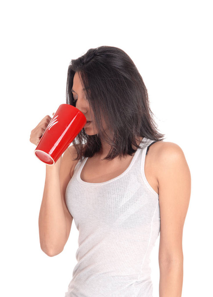 Hispanic woman drinking from a red mug. - Foto, afbeelding