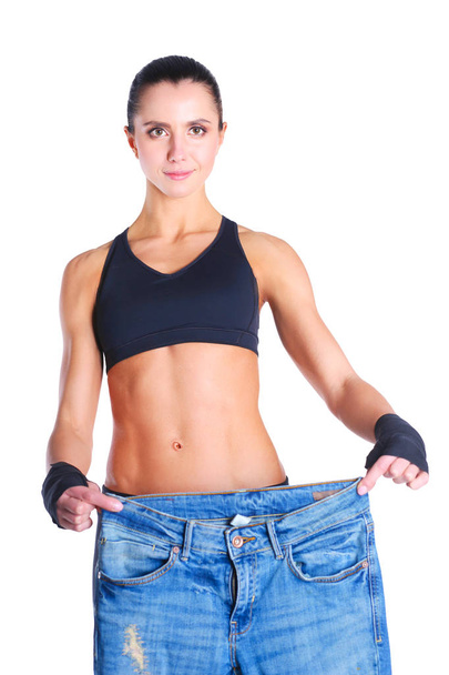 Giovane donna fitness che mostra che i suoi vecchi jeans . - Foto, immagini