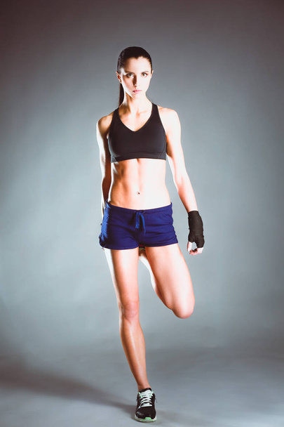 Muscular young woman posing in sportswear against black background. - Fotografie, Obrázek