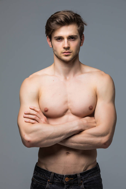 muskulöser Sportler Bodybuilder Mann mit nacktem Oberkörper auf grauem Hintergrund - Foto, Bild