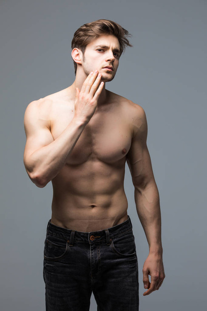 Porträt eines starken gesunden, gut aussehenden, athletischen Mannes Fitness-Modell posiert graue Wand - Foto, Bild