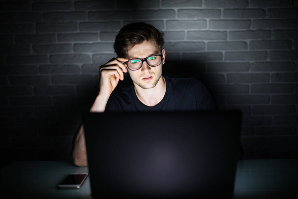 Uomo che lavora a computer portatile nelle mani di notte su occhiali
 - Foto, immagini