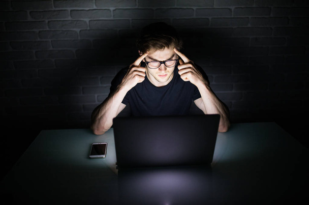 Hombre pensando blanco leer algo en el ordenador portátil en la noche
 - Foto, imagen