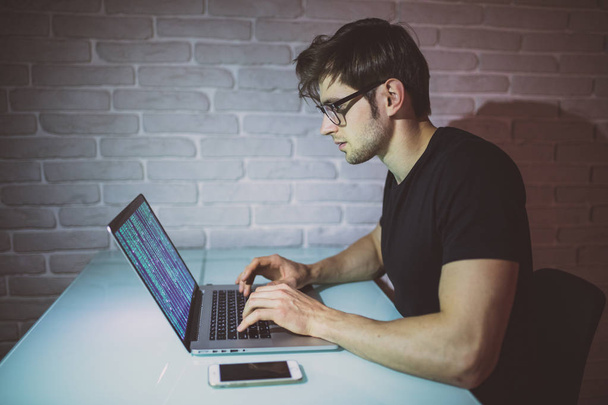 Молодий чоловік програміст працює на ноутбуці вночі і зламує мережу. Молодий хакер атакує мережу вночі
 - Фото, зображення