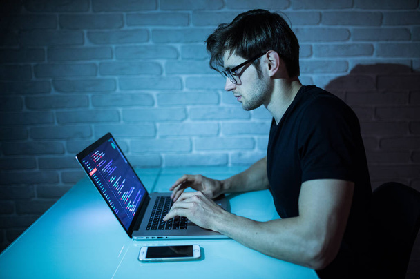 Portrait of hacker with laptop on dark background in the night - Fotoğraf, Görsel