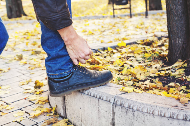 man tying shoelace in autumn park - Foto, imagen