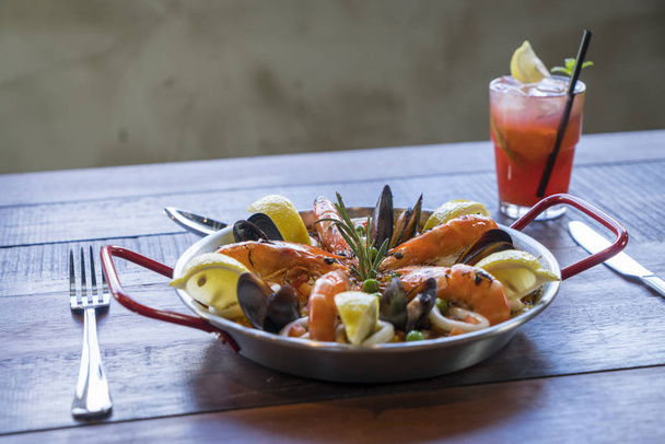 Paella met zeevruchten groenten en saffraan geserveerd in de traditionele pan - Foto, afbeelding