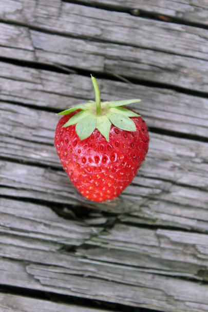 One ripe red strawberrie on an old table - Φωτογραφία, εικόνα