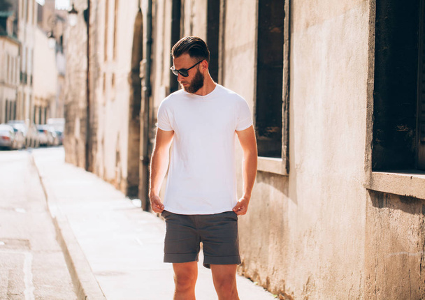 Hipster handsome male model with beard wearing white blank t-shirt with space for your logo or design in casual urban style - Fotografie, Obrázek