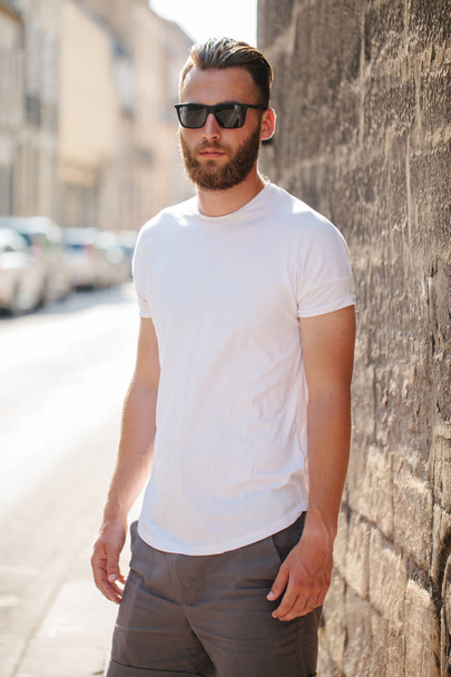 Hipster handsome male model with beard wearing white blank t-shirt with space for your logo or design in casual urban style - Foto, Bild