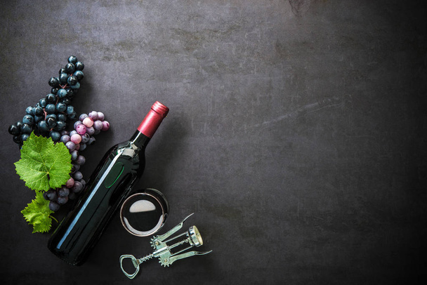 Bottle of red wine, wineglass and grapes - Foto, afbeelding