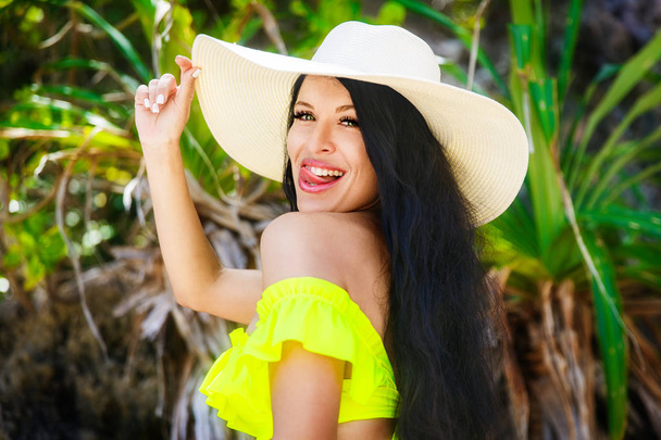 Beautiful brunette with long hair in bikini and straw hat on the - Photo, image