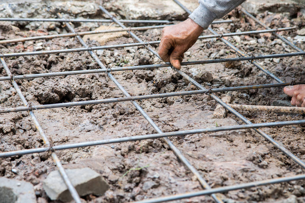 main-d'œuvre attachant la structure de barre d'acier pour le sol sur le chantier
 - Photo, image