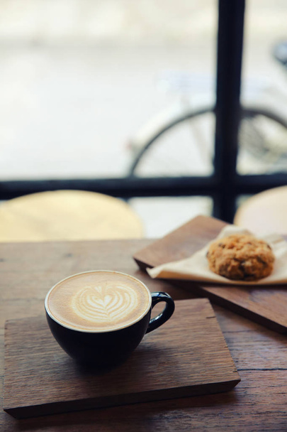 cappuccino coffee with cookie on wood background - 写真・画像