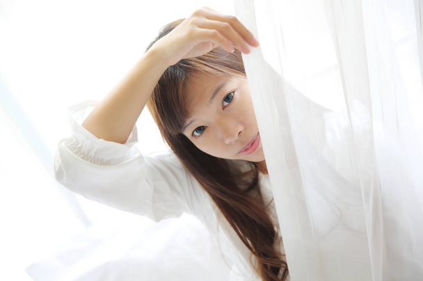 Asiatique jeune femme se réveiller avec oreiller en chambre blanche
 - Photo, image