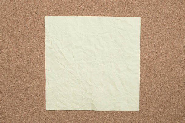 geel gevouwen papier opmerking over kurk achtergrond   - Foto, afbeelding