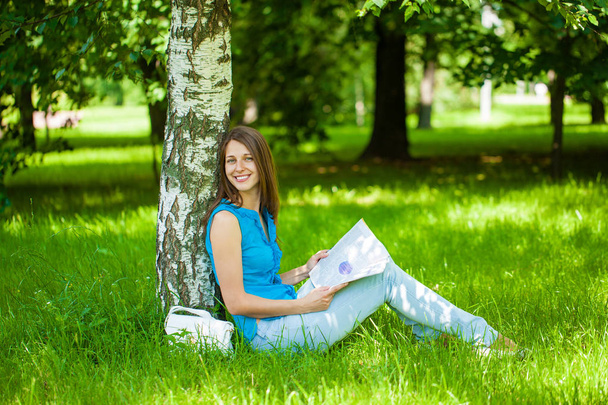 Счастливая брюнетка читает женский журнал, сидя на гр.
 - Фото, изображение