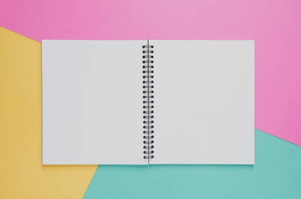 Office workplace minimal concept. Blank notebook on yellow, pink - 写真・画像