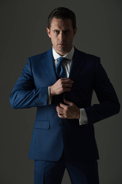 businessman with serious face holding collar in suit - Fotoğraf, Görsel