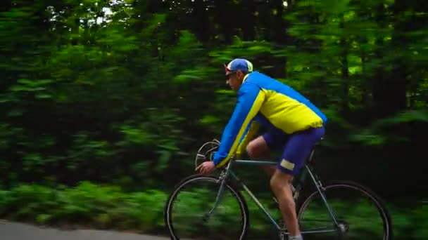 Hombre de mediana edad está montando una bicicleta de carretera a lo largo de un camino forestal, cámara lenta
 - Metraje, vídeo