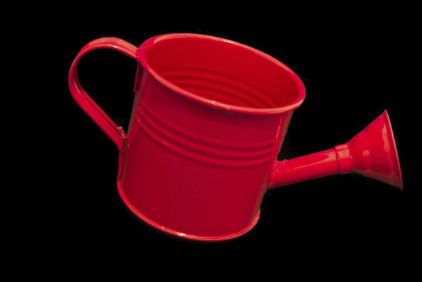Una sola lata de riego rojo aislada sobre fondo negro inclinación dow
 - Foto, imagen