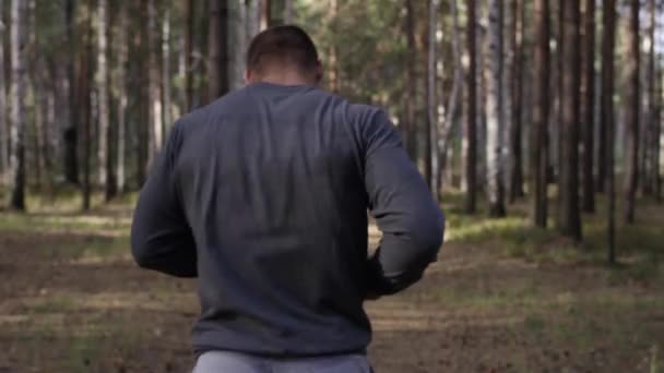 Muscular runner running on road through forest. Back view. Athletic man running on road through forest. Athletic man running on trail through autumn forest - Footage, Video