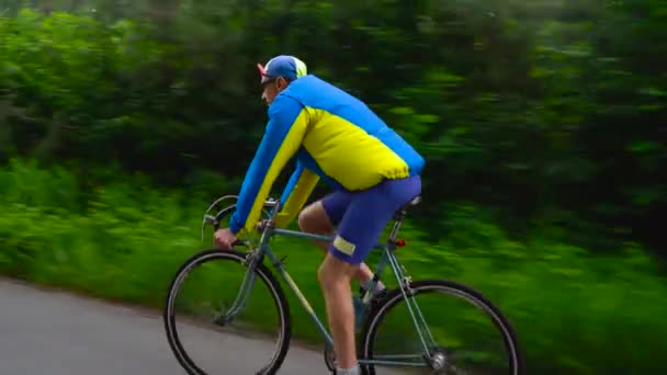 Középkorú férfi a lovaglás egy Országúti kerékpár erdei út mentén - Felvétel, videó