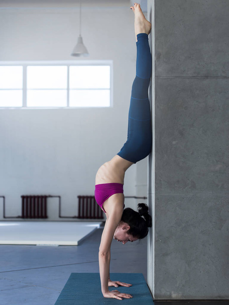 Chica de yoga haciendo soporte de manos con ejercicio backbend en el gimnasio
 - Foto, Imagen