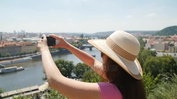 Mujer joven tomando fotos en el teléfono inteligente mientras camina por la ciudad
 - Imágenes, Vídeo