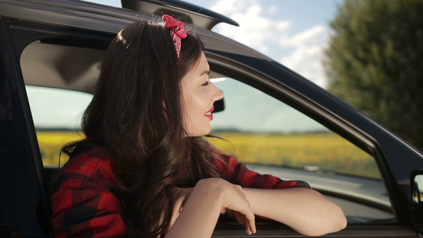 Молода жінка розслабляється на дверях автомобіля під час поїздки
 - Кадри, відео