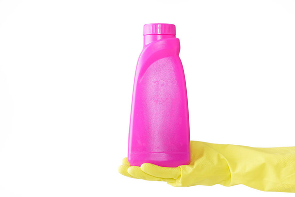 Hand in rubber yellow glove holds pink bottle of liquid bleach on white background. cleaning - Foto, afbeelding