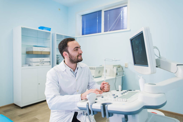 Médico masculino com equipamento ultra-sônico durante o exame médico de ultra-som
 - Foto, Imagem