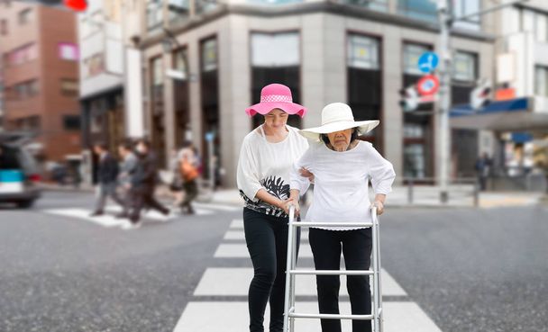 Tochter kümmert sich um ältere Frau, die in der Innenstadt über die Straße läuft - Foto, Bild