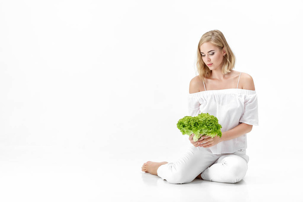 Beautiful blond woman in white blouse holding fresh green salad on white background. Health and Diet - Foto, afbeelding