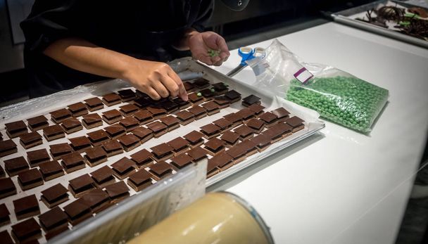 Pastry chef hands decorating mini chocolate square with green ca - Foto, immagini