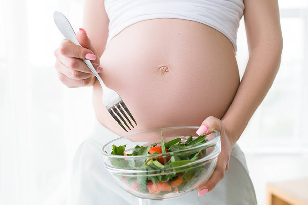 Pregnant woman eats fresh salad - Foto, afbeelding