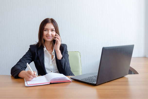 Business woman with notebook, calendar and mobile phone at work. - 写真・画像