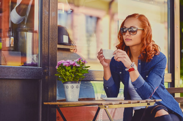 Redhead female drinks coffee in a cafe - Fotoğraf, Görsel