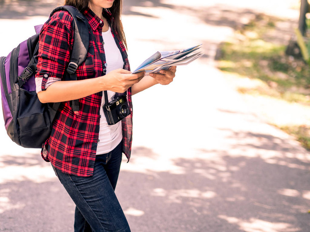 Happy Asian girl holding map with backpack in the road and forest background, Relax time on holiday concept travel ,color of vintage tone and soft focus - Fotoğraf, Görsel