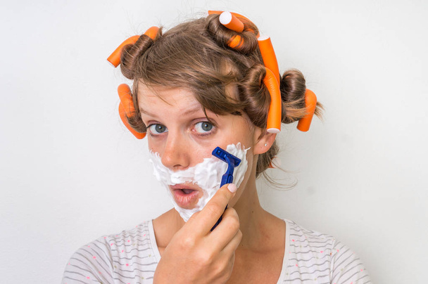Young woman shaves her face with foam and razor - Photo, Image