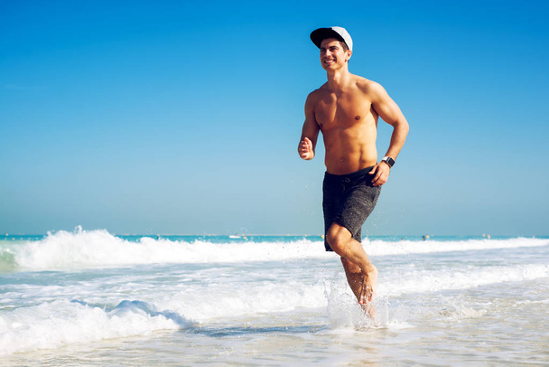 Muscular man running on beach - Φωτογραφία, εικόνα