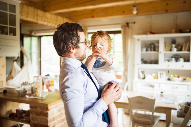Businessman coming home, holding his son high in the arms. - Foto, immagini
