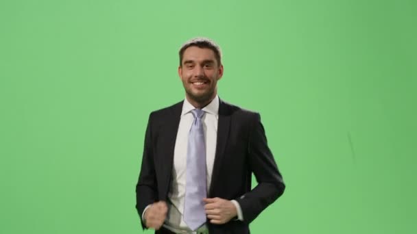 Happy businessman in a suit is running on a mock-up green screen in the background. - Video, Çekim
