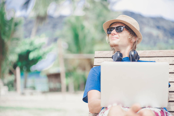 Handsome man working with laptop at the beach - 写真・画像