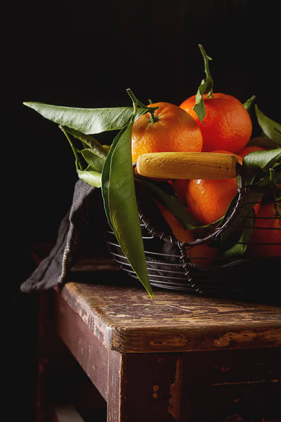 Orange ripe tangerine on the green branch with leaves. Dark wood - Foto, Imagen