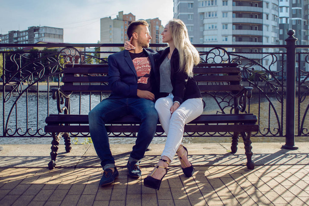 Mladí dospělí muž a žena na lavičce ve městě. Romantický den - Fotografie, Obrázek