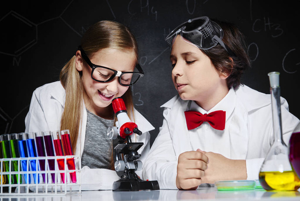 Duas crianças na aula de química
 - Foto, Imagem