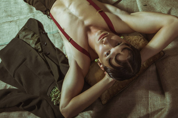 A young and sexy naked guy lies on the floor and looks in the eye - Foto, afbeelding