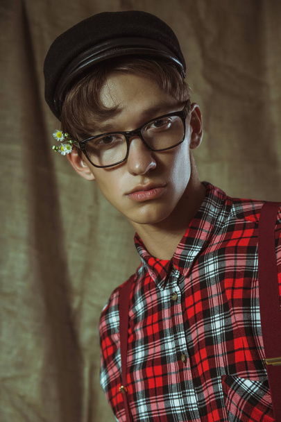 Um jovem de boné preto, óculos e flores atrás da orelha
 - Foto, Imagem